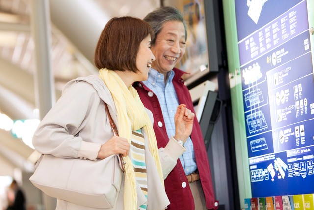旅先で案内板を見るシニア夫婦