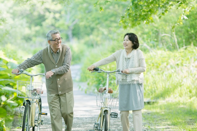 新緑のなか、自転車をおすシニア夫婦