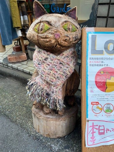 お店の前には目を引く木彫りの看板猫