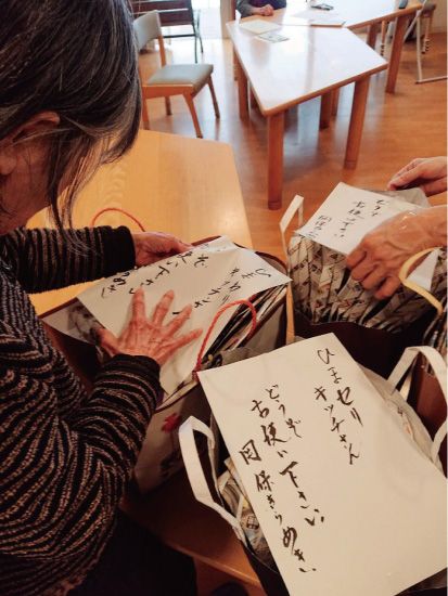届ける新聞エコバッグに一筆を添えるメンバーさんたち