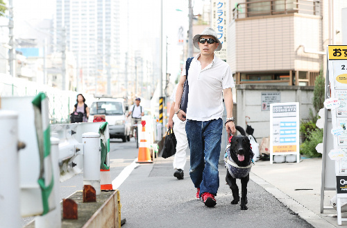 出勤するため、自宅の最寄り駅に向かう金子聡さんと盲導犬のエクルス=8月23日、東京都豊島区