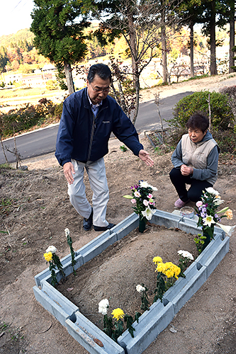 文太の眠る場所で思い出を語る吉田健一さんと貞子さん。貞子さんの願いで庭にお墓を設けた=11月、福島県葛尾村