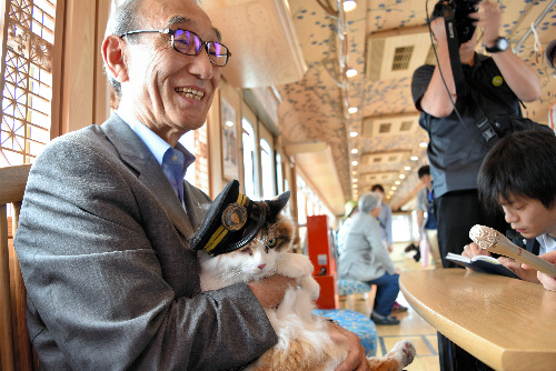 うめ星電車の車内でくつろぐニタマと小嶋光信・和歌山電鉄社長=和歌山市伊太祈曽