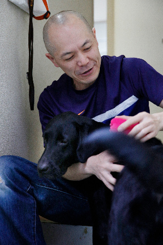 出勤前に盲導犬のエクルスをブラッシングする金子聡さん=8月23日、東京都豊島区