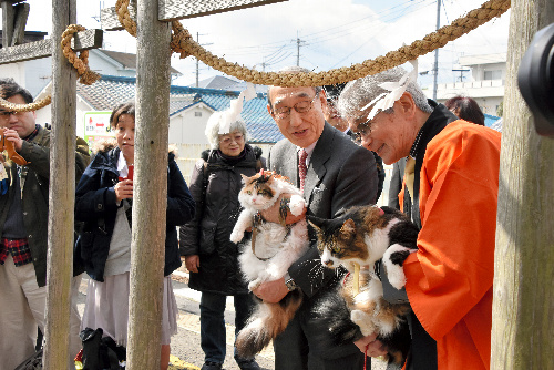 貴志駅構内の「たま大明神」を参拝するニタマ駅長とジュリアーノ市長(右)