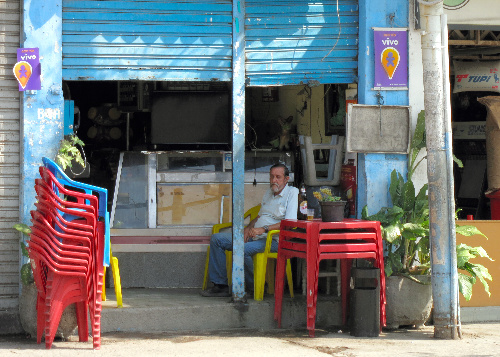 半分だけシャッターが開いた店先で、ビール瓶を傍らに置いて昼寝するおじさん