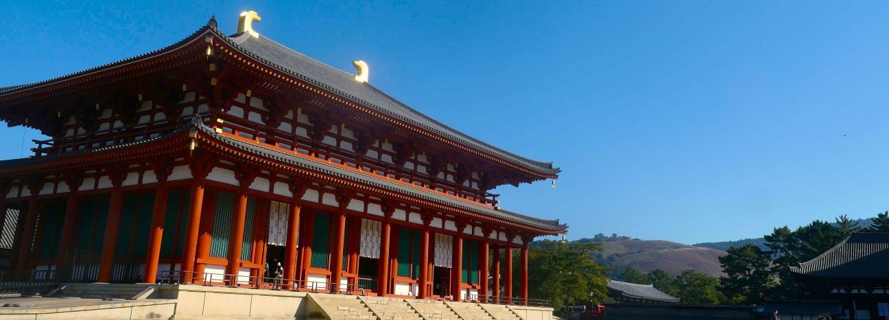 青空の下、前景に興福寺中金堂、遠景には若草山を望む風景写真