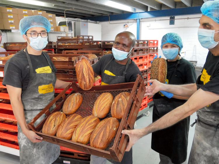 焼きたてのライ麦パン「サワードー」を見せるジャン・ロバートさん（左から2人目）、マドゥさん（同3人目）ら=2021年2月3日、シドニー、小暮哲夫撮影
