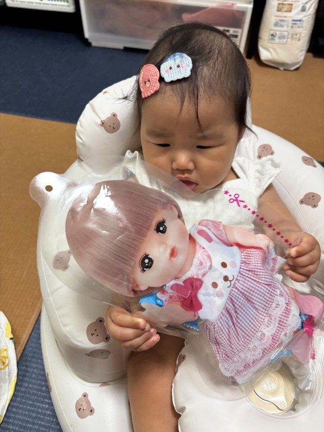 お向かいのおじいちゃんからもらった、メルちゃんのパッケージ入りのたまごボーロを手にする娘。近所の人たちが成長を温かく見守ってくれているという／「あーちゃんちゃん」さん（@aydayo221）提供
