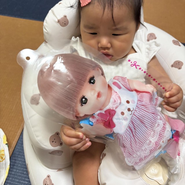 お向かいのおじいちゃんからもらった、メルちゃんのパッケージ入りのたまごボーロを手にする娘。近所の人たちが成長を温かく見守ってくれているという／「あーちゃんちゃん」さん（@aydayo221）提供