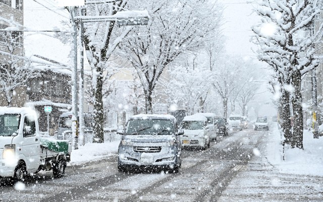降りしきる雪の中、速度を落として行き交う車（２１日午前８時５６分、京都市北区）