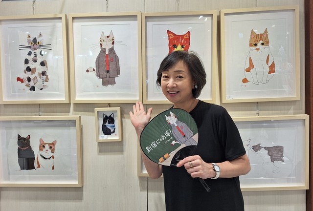 「新宿にゃあ博」で自作の絵を前に、自ら描いた猫デザインうちわを手にする川上麻衣子＝都内の小田急百貨店新宿店７階