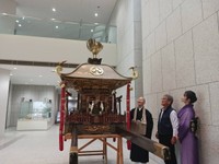 兵庫県立歴史博物館に展示されたお神輿と、それを見つめる（左から）松山住職と福田棟梁、黒島支援隊代表の稲垣さん（提供：黒島支援隊）