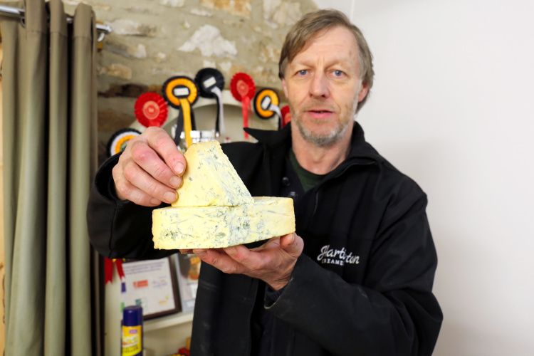 スティルトンチーズを手に持つロバート・ゴスリングさん=2021年3月3日、英中部ダービーシャー、和気真也撮影
