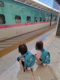 新幹線のリュックを背負い、はやぶさを見つめる子どもたち。家族で東京駅へ見学に訪れたという／MOEさん（@hoppe.mochimochi）提供