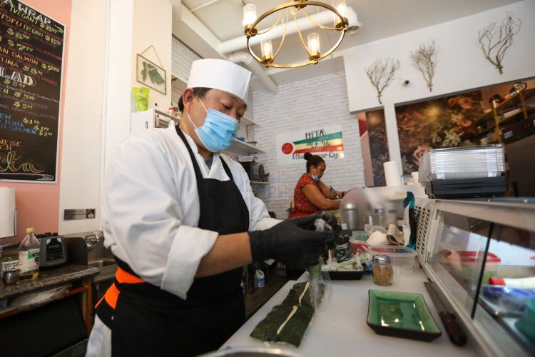 手前ですしを握る井上さん（左）と奥でパニーニを作る奥さんのミスラックさん=ワシントン、ランハム裕子撮影
