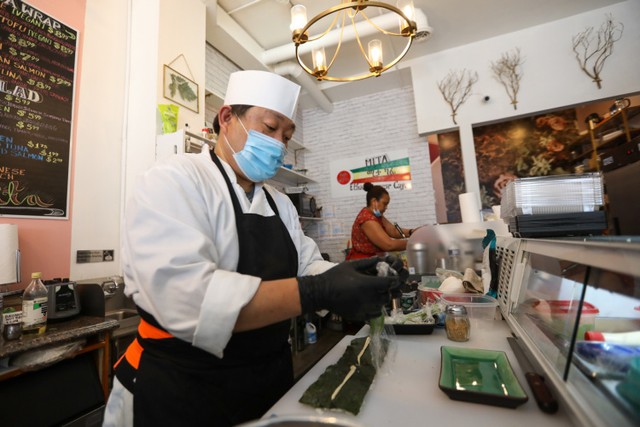 手前ですしを握る井上さん（左）と奥でパニーニを作る奥さんのミスラックさん=ワシントン、ランハム裕子撮影
