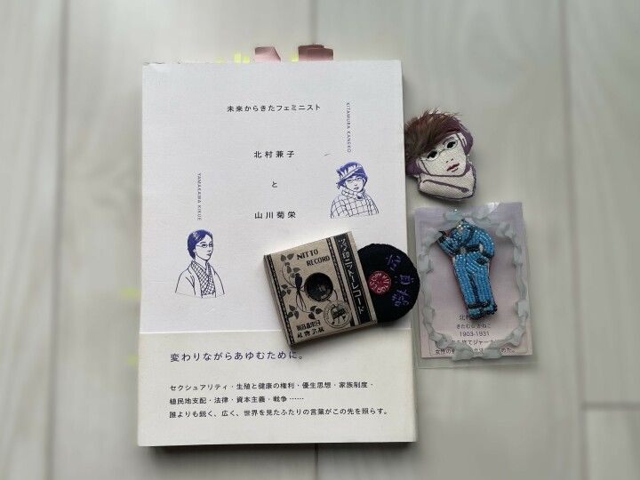 『未来からきたフェミニスト　北村兼子と山川菊栄』（2023年）。左下は、寄稿してくれたmaccaさん作、北村兼子ブローチ３種
