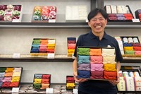 色とりどりの風呂敷に包まれたギフト用のお米「十二単『満開』」と、代表・橋本儀兵衛さん