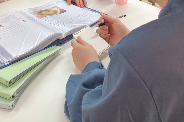 スタッフと一緒に、一人暮らしに役立つ知識などを学ぶ女性。料理も楽しくなったという＝神戸市中央区