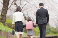 桜の下、手をつないで歩く親子