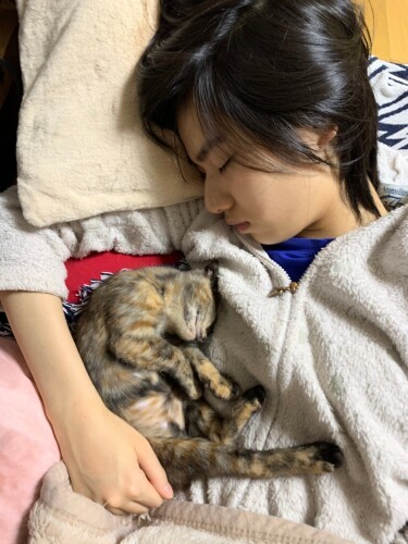 カスレを抱いて寝る大学生の日向ちゃん。「預かりのカスレを私が自分で飼いたいといったので、バイトをして避妊手術代をためました」（知枝さん提供）