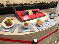 巨大なワニ（サメ）の生け作りと、ユッケなど様々なワニ（サメ）料理のサンプルが並ぶ