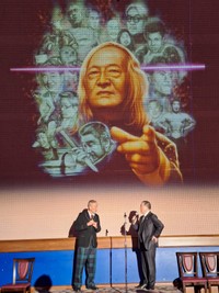 ２月10日に都内で開催された「康芳夫を偲ぶ会」で登壇者の頭上に写し出された新刊「冥界へのメッセージ」の表紙デザイン