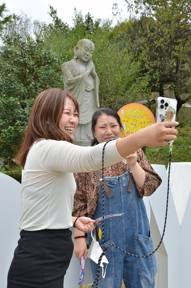 ハッピー地蔵さまの前で自撮りするをする観光客。既に人気のスポットとなっているようで、地蔵も幸せそうだ