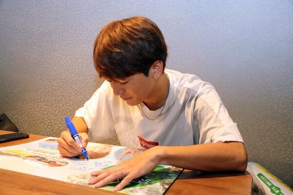 京田辺市をＰＲするポスターにメッセージを書き込む大倉さん（京田辺市提供）