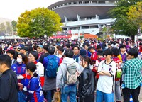 ファジフーズに並ぶサポーターら。ＦＣ東京のユニフォーム（青と赤）も目立つ＝４月６日、ＪＦＥ晴れの国スタジアム前