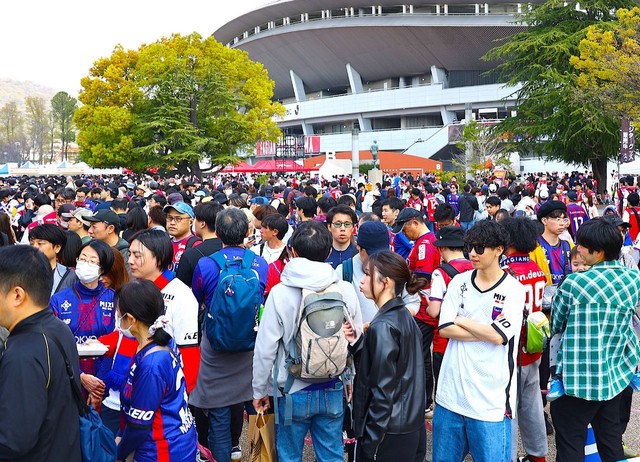 ファジフーズに並ぶサポーターら。ＦＣ東京のユニフォーム（青と赤）も目立つ＝４月６日、ＪＦＥ晴れの国スタジアム前