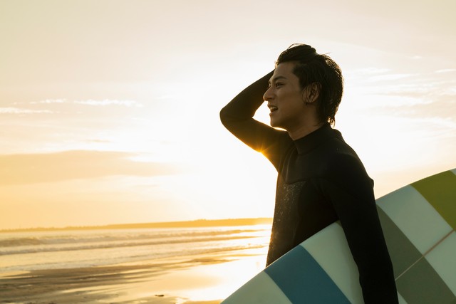 海でサーフィンをする男性※画像はイメージです（One/stock.adobe.com）