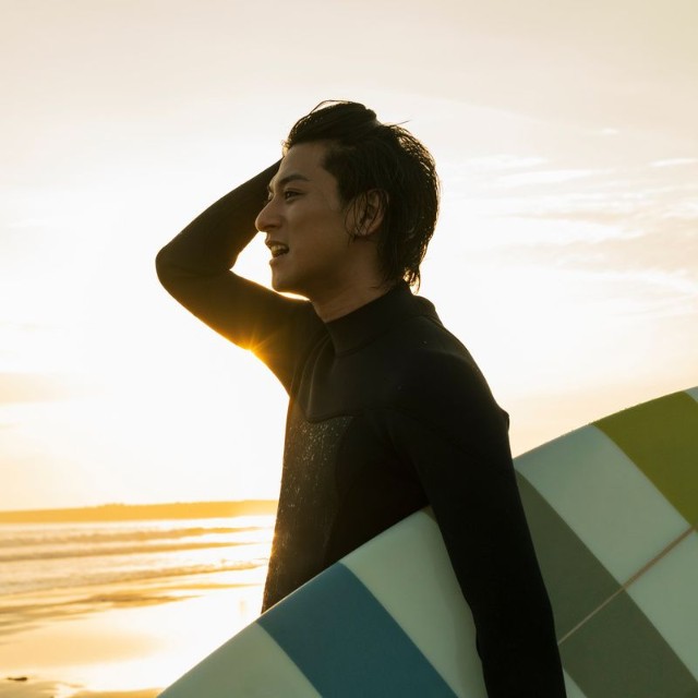 海でサーフィンをする男性※画像はイメージです（One/stock.adobe.com）
