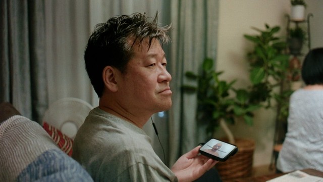 父親役を演じた佐藤二朗。手に持ったスマホにはハリウッドザコシショウの姿が＝大塚製薬「カロリーメイト」の受験生応援CM「いちばんの味方」編より