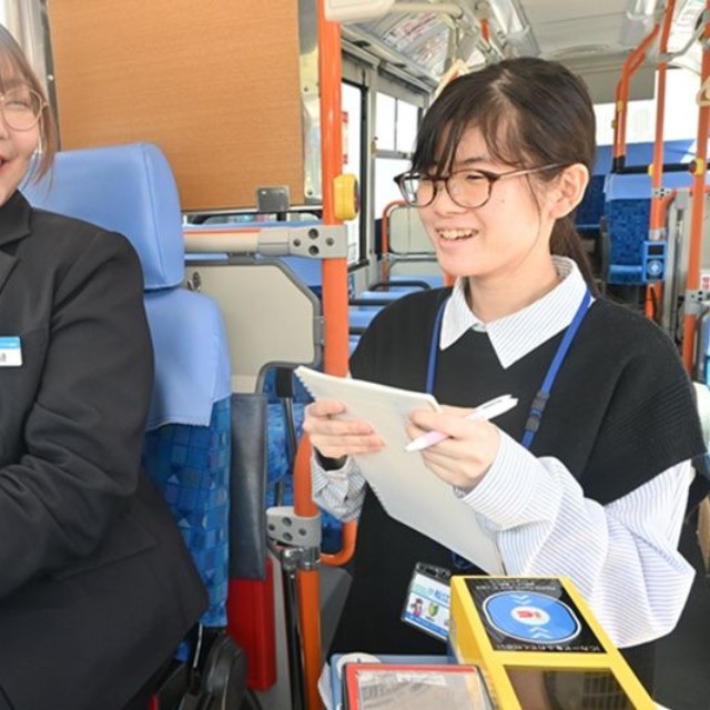 先輩の運転手から乗客の対応について学ぶ山本夏楓さん（右）＝島根県松江市、市交通局