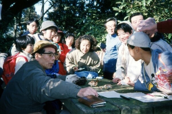 参加者らにキノコを見せながら解説する吉見昭一さん（左下）＝１９９６年１２月１５日、京都御苑堺町休憩所（佐野さん提供）