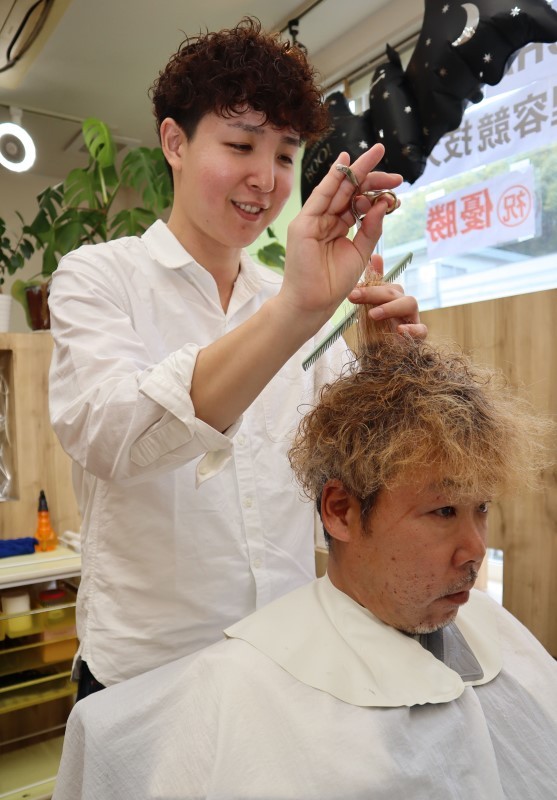 全国理容競技大会で優勝を果たした安井さん（左）