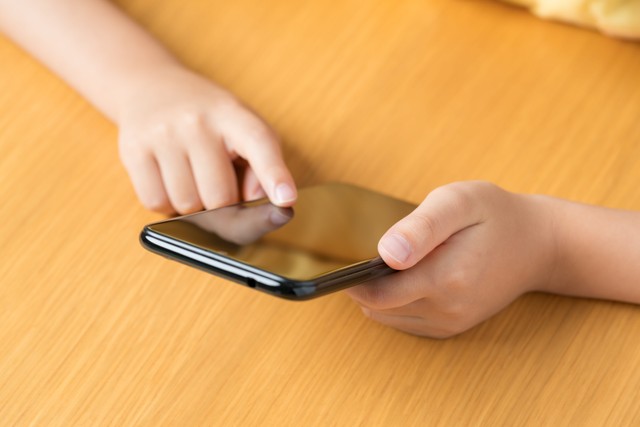 スマートフォンを操作する子どもの手元 ※画像はイメージです（Hanasaki/stock.adobe.com）