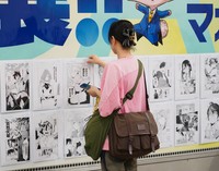 掲載された「フェアリーテイル」の複製原画をピックアップする人