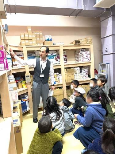 フードストックでの動物の食事の説明。「具合が悪くて食べられないときもある、そんなときはどうする？」と子供たちに質問。職員で獣医師の山本さん