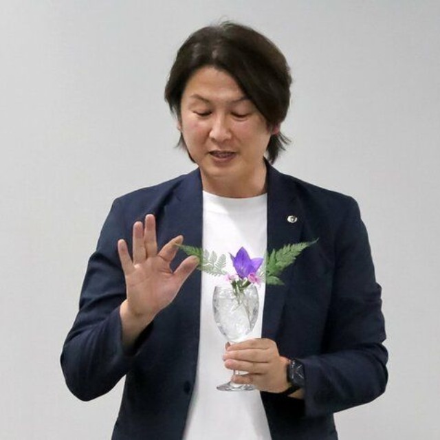 ワイングラスに花を生けて「いけばなは生活文化でもある」と説明する藤井さん