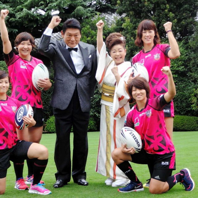 女子ラグビー選手たちとトライを決めガッツポーズを決める増位山太志郎（左）と中村美律子＝2014年