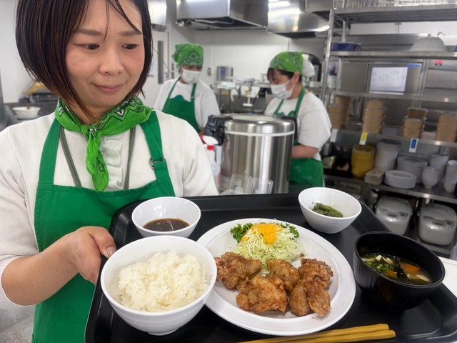 一番人気の唐揚げがメインの定食。岩崎さん（左端）らが食堂を切り盛りする＝９月１６日、倉敷市平田