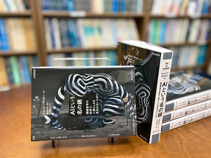 装画解説：作品名「Narcissus Stares into the Water #01」ギリシャ神話に登場するナルキッソスをモチーフとした、松山しげき氏の彫刻作品。ナルキッソスは、水面に映る自らの美しさに魅了され、ついにはそこから目を離せなくなり、命を落とした。彼が愛したのは、見えてはいても触れることのできない、実体のない像である。同様に現代の私たちも、スマートフォンの画面に流れる膨大な情報や、AIが返す“もっともらしい応答”に引き込まれている。それらは外から与えられた知や理解のように見えながら、実際にはバイアスを含んだ「過去の自分」をなぞった像にすぎない。
ナルキッソスの物語が示すのは、像そのものの危険ではなく、それを現実と取り違え、距離を失うことの危うさである。AIと向き合う私たちにもまた、その距離感が問われている。