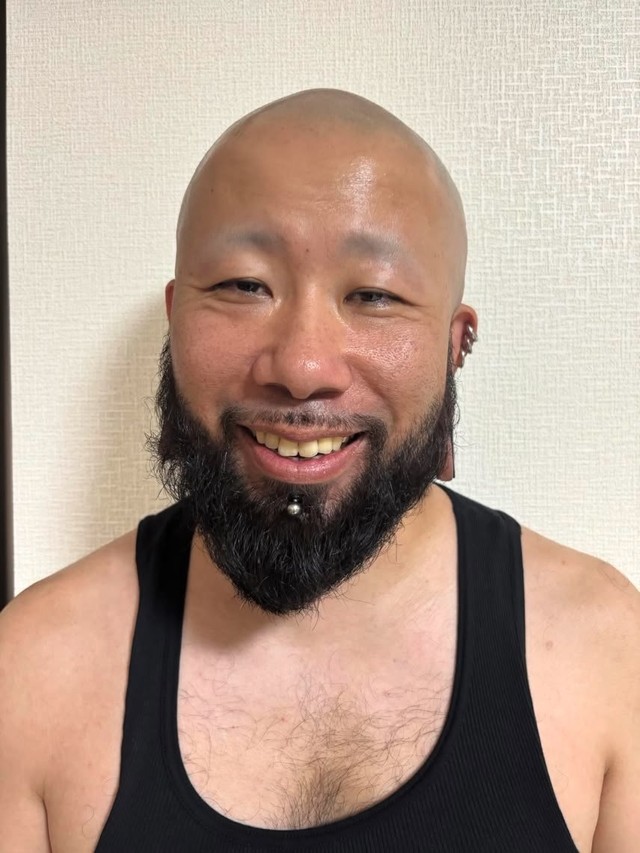 2026年2月現在の、ゆう也さん。スキンヘッドと立派な髭、大きなピアスが印象的／Akimoto MINMIさん（@akimoto_family）提供