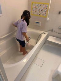 浴槽に入ってシャワーでお風呂掃除をする女の子（まゆこさん提供）