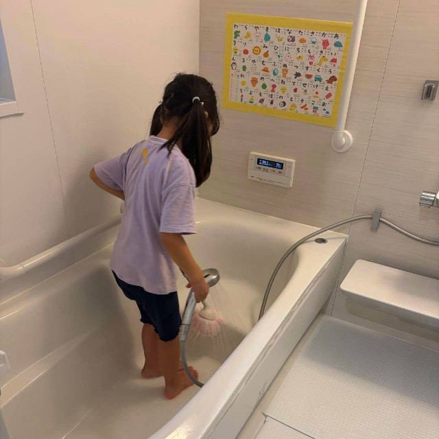 浴槽に入ってシャワーでお風呂掃除をする女の子（まゆこさん提供）