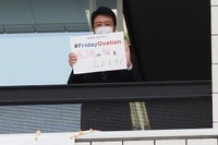 「感謝の輪を広げよう！」と書いたメッセージボードを掲げる高島市長