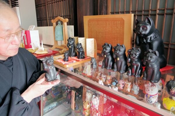 授与している招き猫を手にする信ケ原住職（京都市左京区・檀王法輪寺）